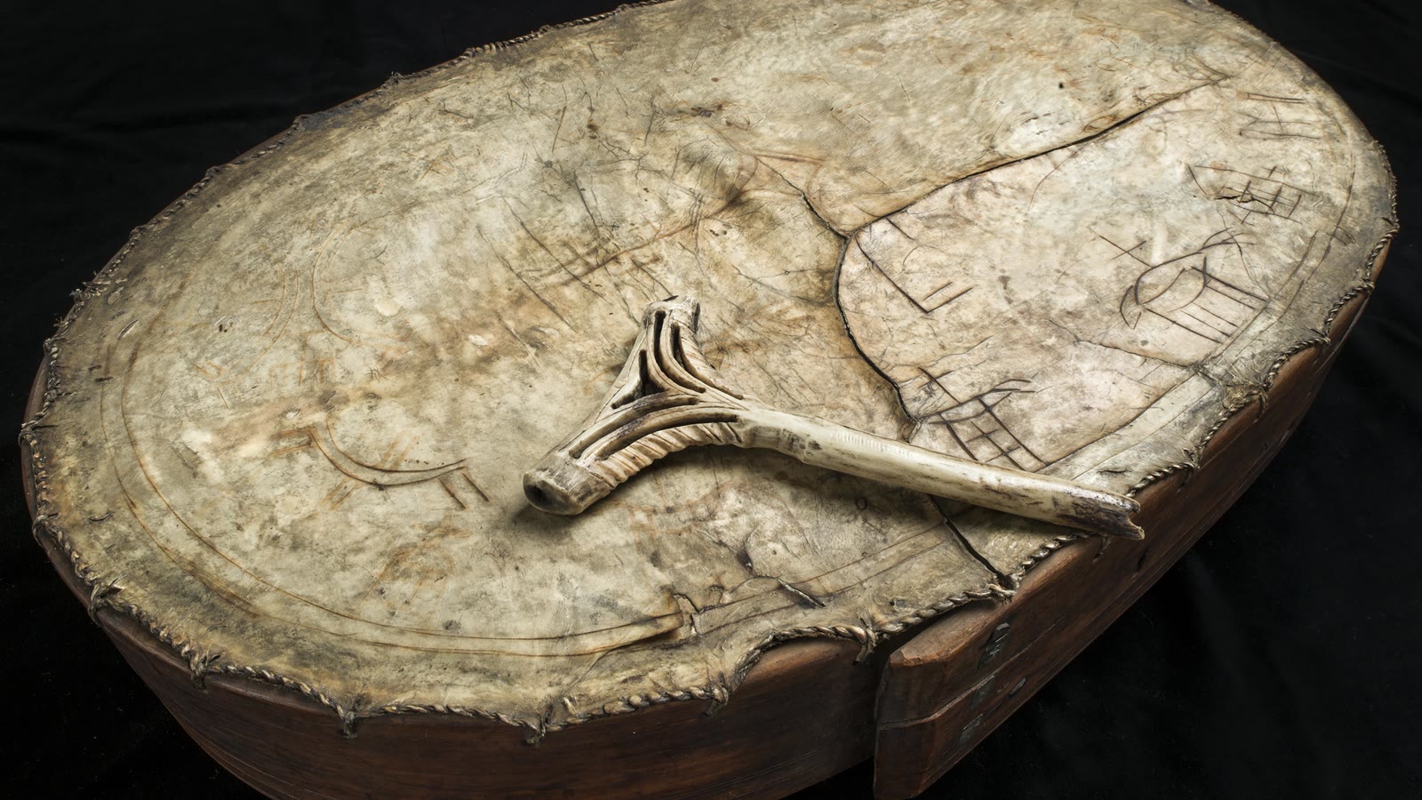 Sydsamisk runebomme (trommeskind med malede symboler og en slidt trommehammer af ben) fra 1700-tallet, fotograferet på museum